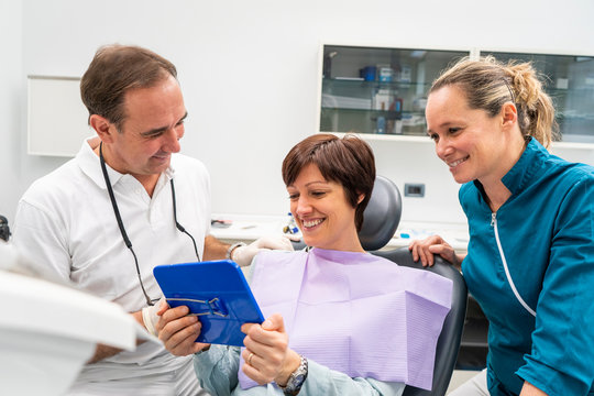 Happy Woman Patient With Dentist Doctor Looking At Mirror In Clinic