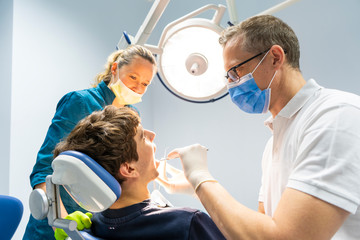 Professioneller Zahnarzt und Assistent, der eine Zahnoperation in einer Klinik mit moderner Werkzeugausrüstung durchführt