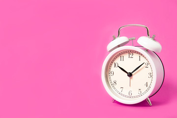 White alarm clock on a pink background. Place for text