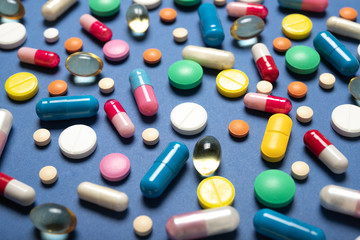 Multi-colored pills on a blue background. Medicine and health.