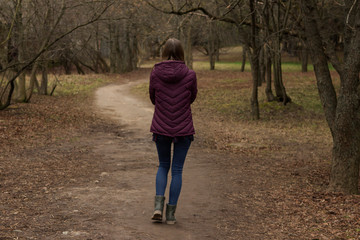 Obraz premium A lonely long-haired fair-haired teen girl walks through a dark forest alone.