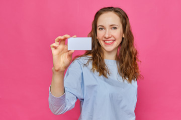 Stylish caucasian girl in a pale blue t-shirt holds a white card in his hands and sends it to the...