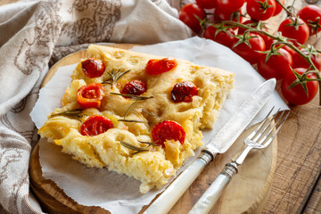 Piece of savory focaccia with olive oil, rosemary and cherry tomatoes