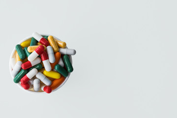 White container full of colored capsules, top view, space for advertising. Concept of virus prevention.