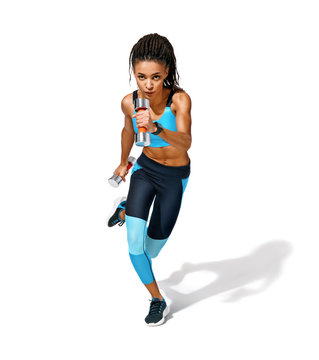 Sports girl doing exercise with dumbbells. Photo of african american girl in fashionable sportswear on white background. Dynamic movement. Side view. Full length. Sports and healthy lifestyle