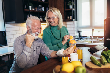 Seniors couple at home measuring blood pressure and make healthy juices. Home monitoring