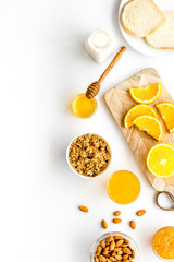 Morning granola near toast and oranges on white background top-down frame copy space