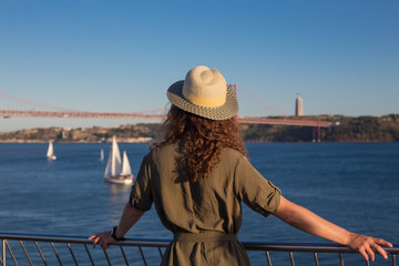 Young woman looking at bridge Ponte 25 de Abril Lisbon
