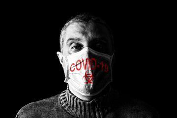 Man with surgical mask. Biohazard and COVID-19, aka Coronavirus symbol. Pandemic or epidemic and scary, fear or danger concept. Black Background