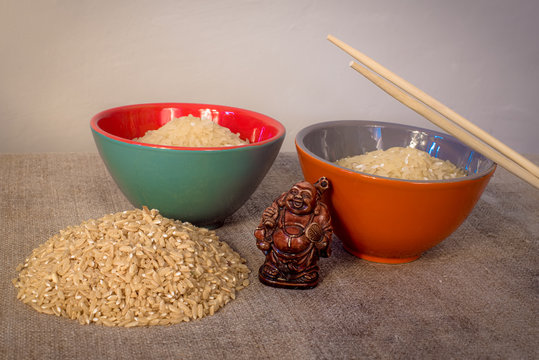 Asian traditional cuisine. The rice in the plates is on the table. Wooden figure of netsuke