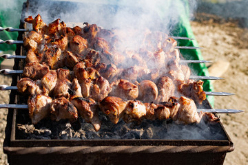 Mouth- watering skewers of pork with a toasted Golden crust and smoke flavor. Barbecue with coals in the yard in nature with cooked meat on skewers