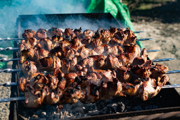 Mouth- watering skewers of pork with a toasted Golden crust and smoke flavor. Barbecue with coals in the yard in nature with cooked meat on skewers