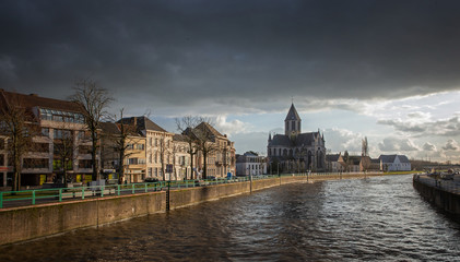 Quay at river Schelde Belgium. Canal in the city of Oudenaarde. Dark clouds.
