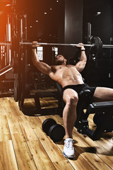 Young muscular man lifting a barbell bench press in the gym. Sport, movement, life. The concept of...