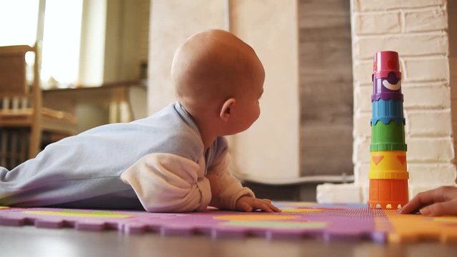 Mother teaches baby to crawl on the carpet in the house. Mother develop baby