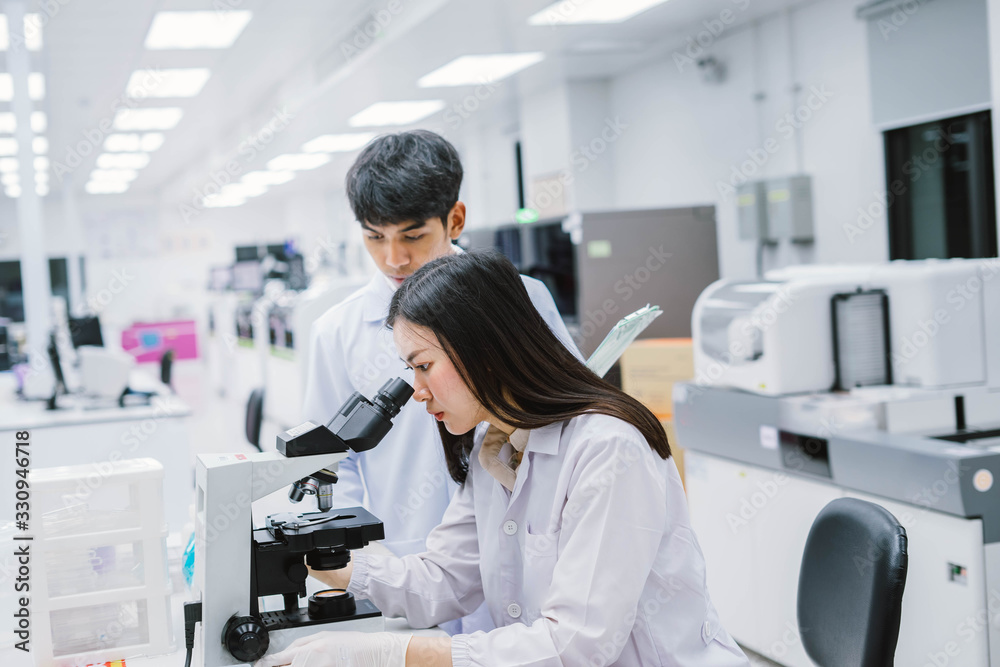 Wall mural two medical scientist working in medical laboratory , young female scientist looking at microscope. 