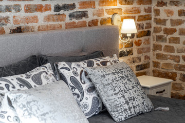 Modern loft interior of luxury bedroom with brick walls. Close-up of pillows on the bed.