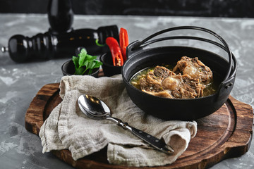 Shurpa soup in a cast-iron pot on the table on a gray background. Traditional oriental cuisine.