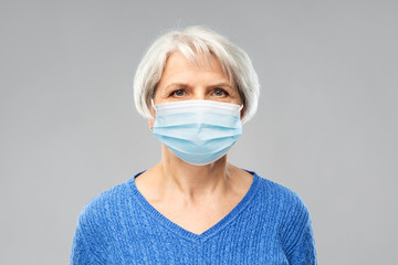 health, safety and pandemic concept - portrait of senior woman wearing protective medical mask for...