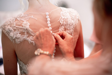 Bride getting dressed, detail photo of back of button dress, buttons being done