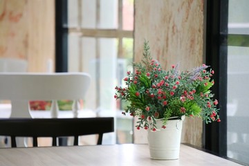 Blurred of interior of the restaurant with white pot of bouquet flower on the wooden table. Interior and background concept.