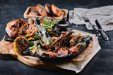 Assorted seafood on plates. Beautiful composition on a served seafood table, squid, shrimp, salmon steak and octopus. Food photo, low key, traditional Italian cuisine. Top view, save the space