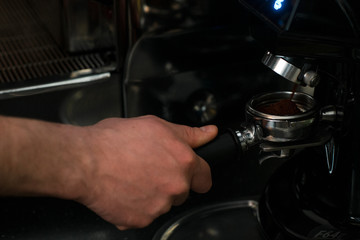 barista picks up a serving of freshly ground coffee