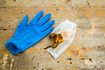 white medical protection mask with blue medical glove which are set on fire after use as a symbol...