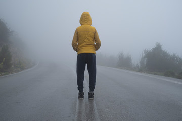 A facing back hoody boy hands in pocket, standing in an abondoned road in air pollution, foggy...