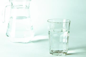 Pure clear water in a glass and jug stands on a white background