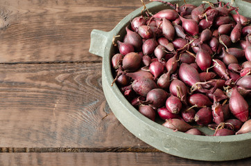 Red seeding onion on concrete dish on wooden background with copy space