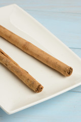Canela en rama en un plato en la mesa azul