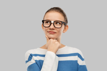 school, education and vision concept - smiling teenage student girl in taped glasses thinking over...