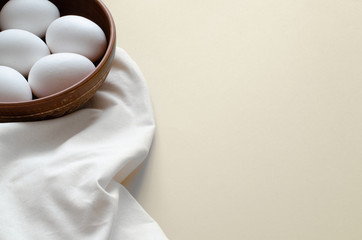 Chicken eggs in bowl and linen on light background with copy space