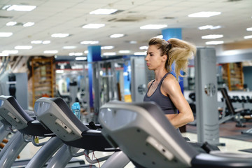 Fototapeta na wymiar Young sporty Woman On Running Machine In Gym