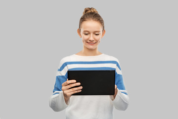 technology, communication and people concept - happy smiling teenage girl in pullover using tablet pc computer over grey background