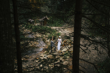 wedding couple walks near a mountain river - view through trees in the Ukrainian Carpathians