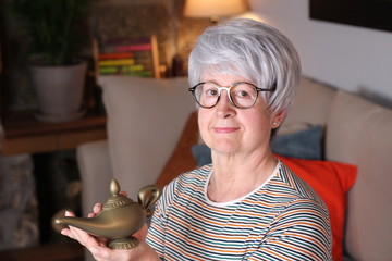 Senior woman rubbing genie lamp - obrazy, fototapety, plakaty