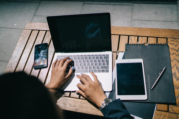 Unrecognizable entrepreneur browsing laptop on street