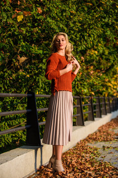 Autumn fashion. female beauty. Femininity and tenderness. sunny day with fallen leaves. fall fashion season. autumn woman outdoor. girl in pleated skirt and sweater. Pleated trend. girl walk in park