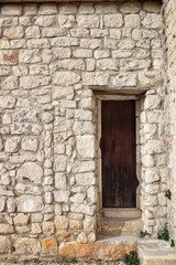 Fototapeta na wymiar Entrance to old stone house. Dark brown wood and stone. Stone steps.