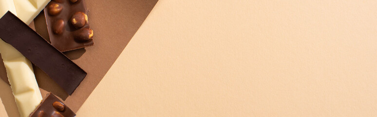 top view of delicious white, milk and dark chocolate bars on beige background, panoramic shot
