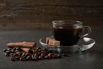 glass Cup of coffee beans with cinnamon and sugar on a dark wooden background