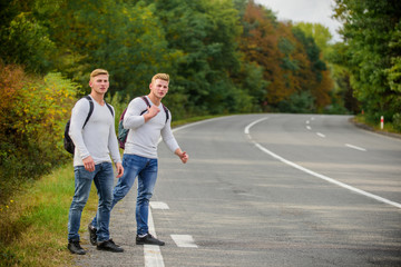 Obraz premium Powód, dla którego ludzie odbierają autostopowiczów. Przegapił ich autobus. Potrzebuję pomocy. Tani transport. Problem transportowy. Koncepcja podróży i transportu. Bliźniacy mężczyźni na skraju drogi tle przyrody. Spróbuj zatrzymać jakiś samochód