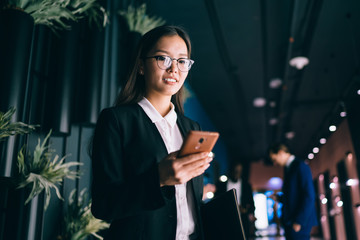 Successful lady watching smartphone at workplace