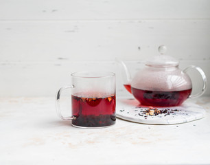 Glass transparent mug and teapot with purple hot hibiscus tea with slices of various dried fruits and berries isolated lifestyle photo