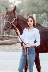Obraz premium Beautiful Asia girl taking care of her horse with love and caring.