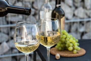 Waiter pouring white wine on outdoor cafe terrace in sunny summer day