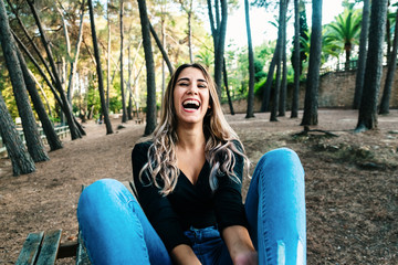 Young woman laughing with a joke sitting in a park.