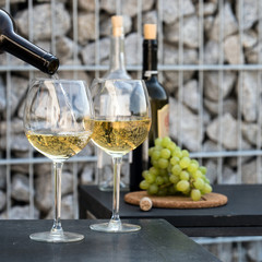 Waiter pouring white wine on outdoor cafe terrace in sunny summer day